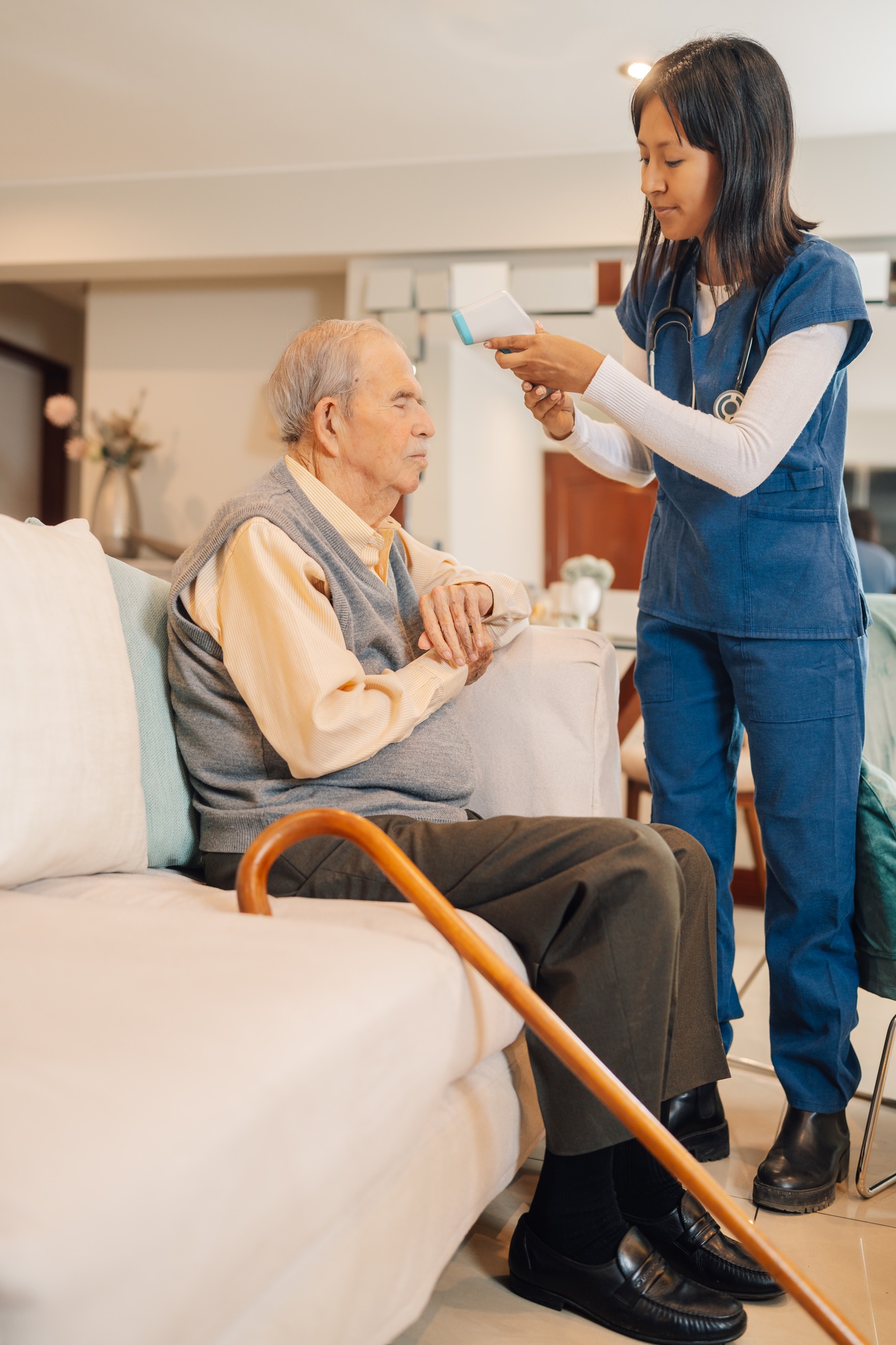 Home health worker measuring the body temperature of elderly man